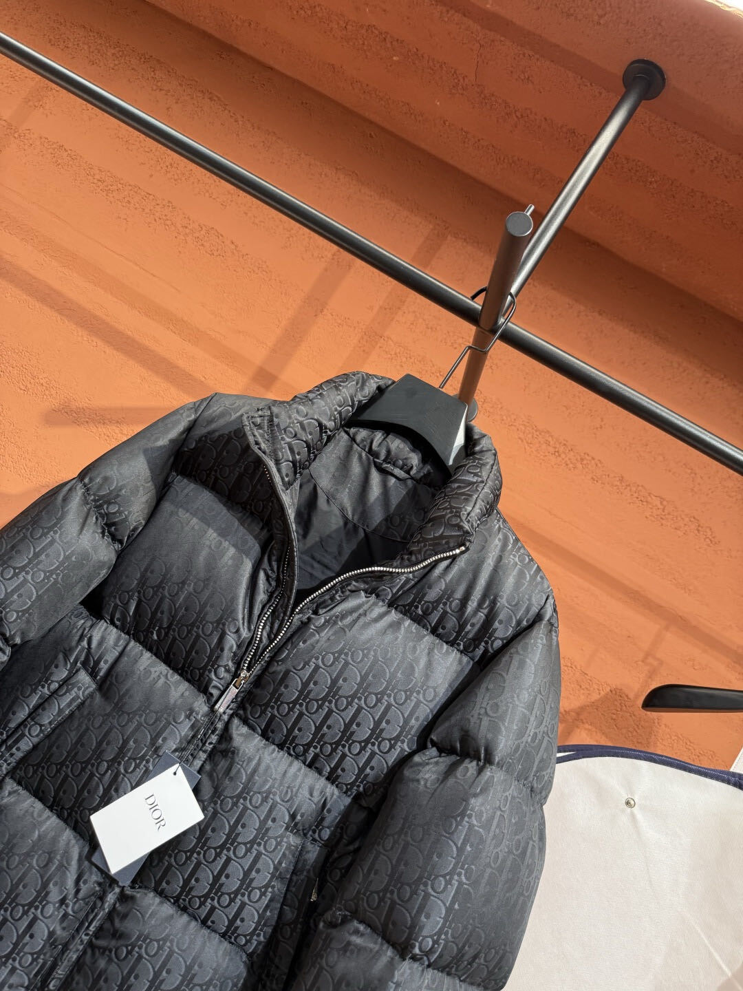Detailfoto van het Dior Oblique monogram en de rits van de puffer jas